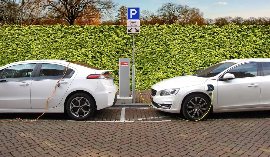 Zwei weiße E-Autos beim Laden. Haben sie ihre Schuldigkeit getan, müssen sie und die Lithium-Ionen-Akkus entsorgt werden.