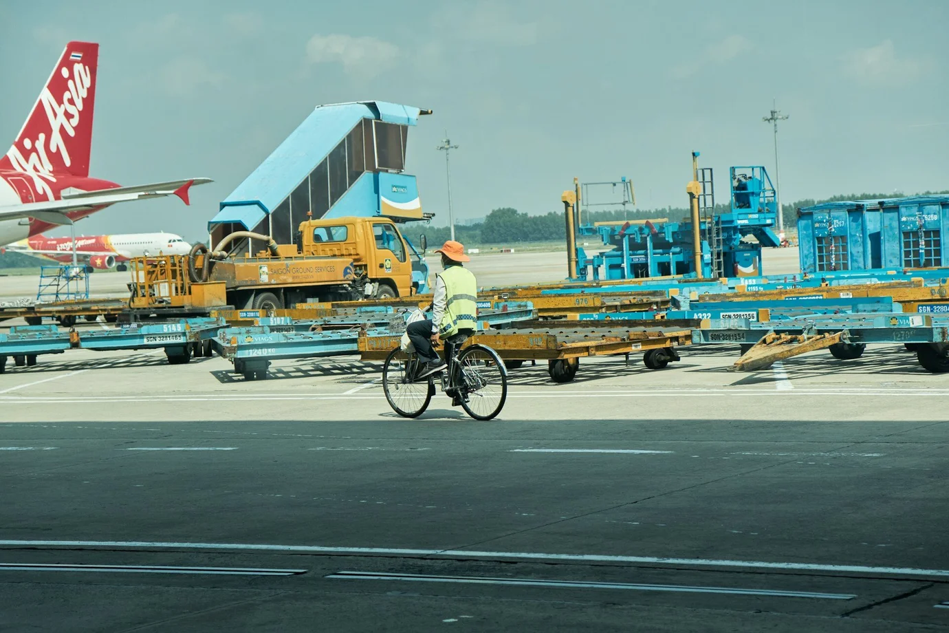 Ein Mitarbeiter fährt mit dem Fahrrad über einen Flughafen. Mit einem E-Bike kommt er nicht ins Flugzeug.