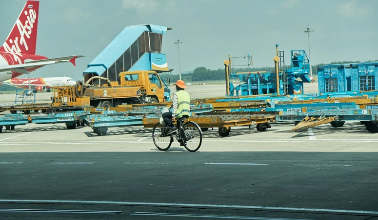 Ein Mitarbeiter fährt mit dem Fahrrad über einen Flughafen. Mit einem E-Bike kommt er nicht ins Flugzeug.