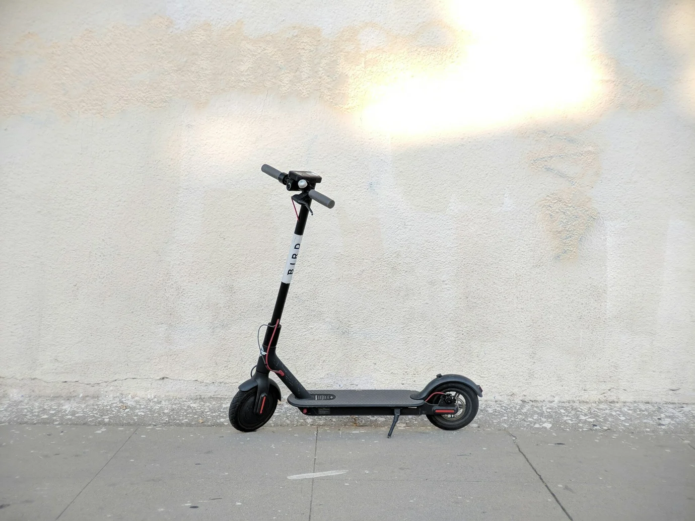 Schwarzer E-Scooter vor beiger Wand. Viele fragen sich, wie und wo man E-Roller aufladen kann.