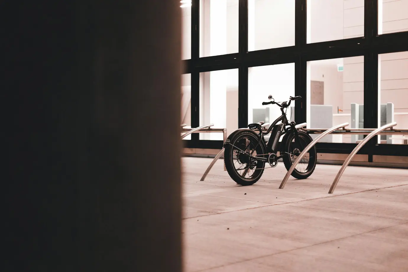 An e-bike with wide tyres is parked in front of a company. Electric bikes can pose a fire hazard, especially when charging.