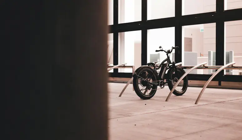 An e-bike with wide tyres is parked in front of a company. Electric bikes can pose a fire hazard, especially when charging.